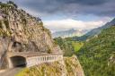 A road goes through a long tunnel carved into the side of a mountain