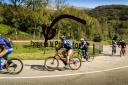 Group of cyclists riding in front of the Prehistory Park in Teverga
