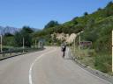A solitary cyclist descending a road in a mountainous environment