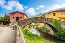 An old stone bridge over a stream that crosses a village
