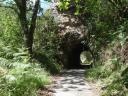 A narrow path passes through a natural tunnel formed by rocks