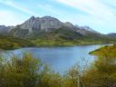 Un amplio embalse rodeado de montañas y vegetación refleja un cielo azul