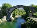 Puente de piedra antiguo sobre un río con aguas verdes