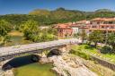 A view from the top of a bridge crossing a river towards a village among mountains