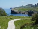 Un camino de tierra recorre los verdes acantilados junto al mar Cantábrico