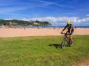 A cyclist on a mountain bike pedaling on the beach near the shore