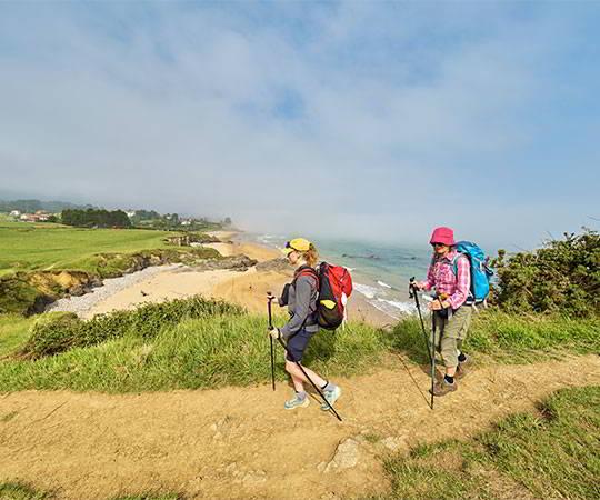 Image of two pilgrims in the vicinity of the beach of El Viso/Moracey in the council of Caravia in the background.