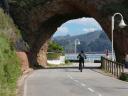 A cyclist arriving at a natural stone tunnel facing the sea