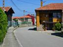 A narrow road turns right with colorful rural houses on both sides