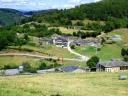 A rural village sits in a green valley under a bright sky