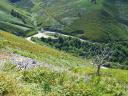 View from the top of a road ascending a green mountain slope