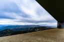 A cyclist admires the views from a modern viewpoint to the peaks of a mountain pass