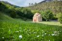 A Pre-Romanesque church in the center of a large meadow covered with grass and flowers