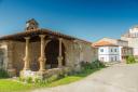 A small stone chapel with arches and a portico in a village
