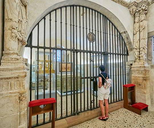 Image of the interior of the Holy Chamber of the Cathedral of El Salvador in Oviedo/Uviéu. A person observes the relics inside.