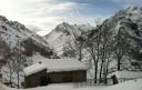 Lonely hut in a snowy valley with steep mountains in the background
