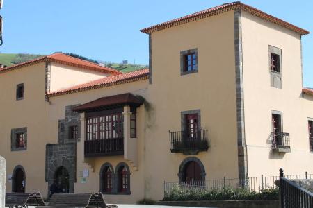 A palace with beige walls, two floors with a closed balcony, and two towers