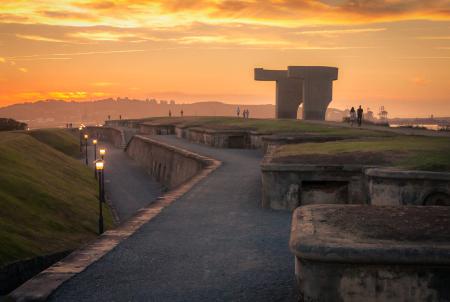 Monumental sculpture at sunset, on a rocky promontory overlooking the sea