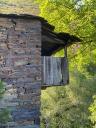 Rustic stone building with wooden details, integrated into the green landscape.