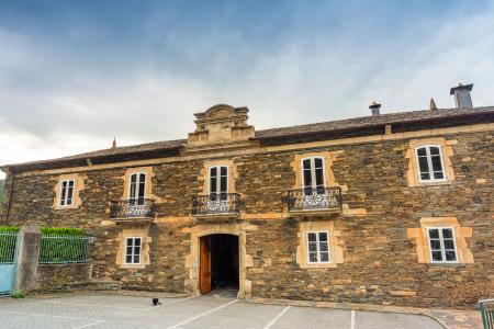 Facade of an old palace with a stone-carved coat of arms, three balconies, and eight windows