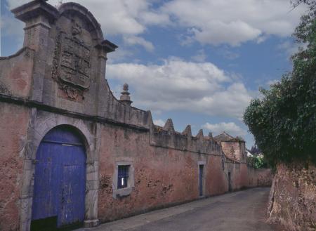 Long wall and entrance of an old palace with a large coat of arms and a blue door