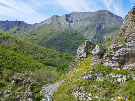 Vista panorámica de un valle verde con montañas escarpadas y cielo azul