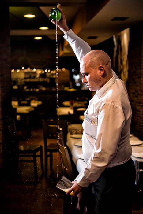 Image of a cider pourer in the foreground pouring cider into a glass.