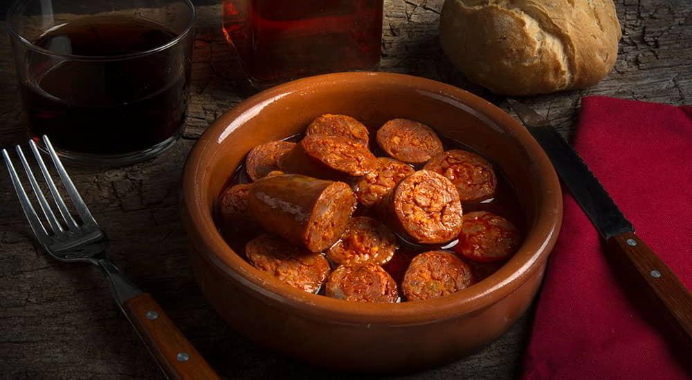 Dish of chorizo in cider in the foreground.