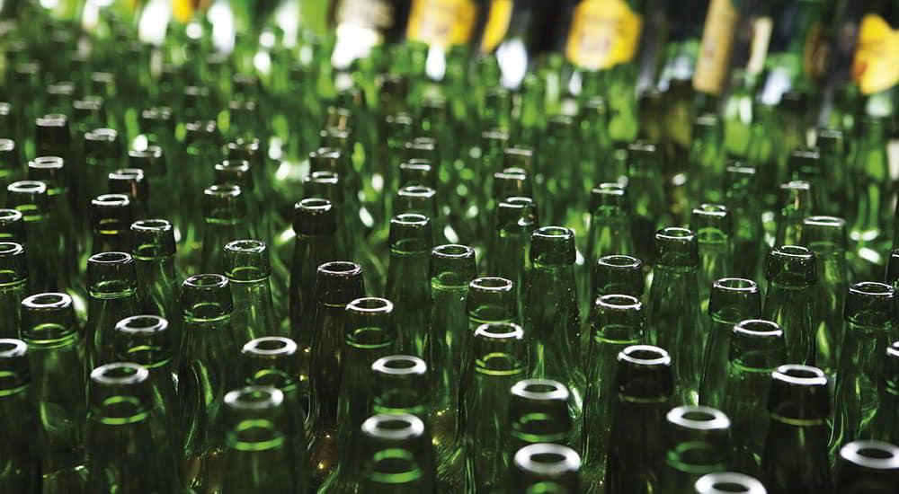 Cider bottles in the bottling process, in the foreground, ready to be filled with cider.