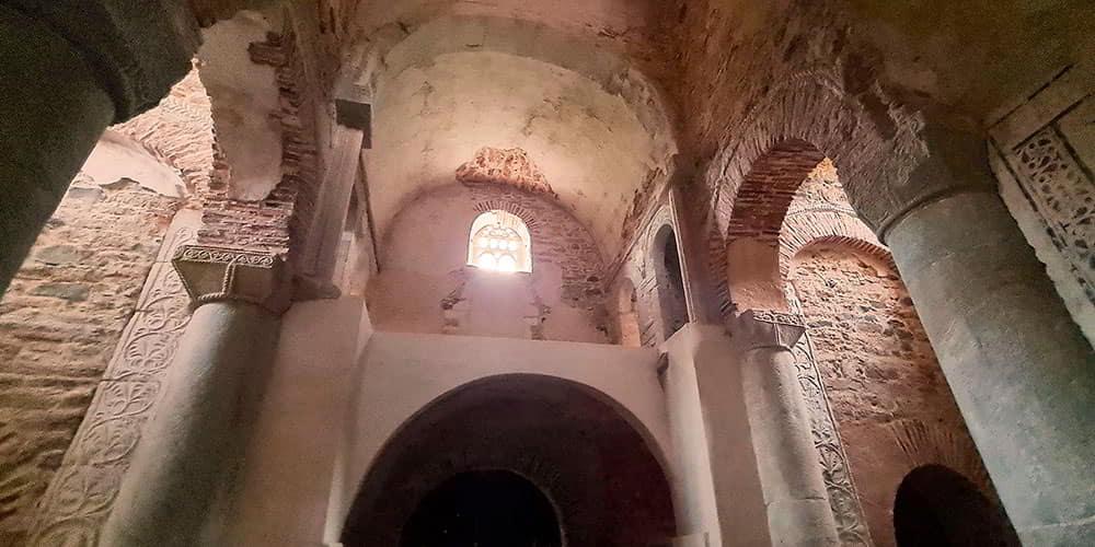 View of the interior of San Miguel de Lillo, showing the royal tribune, the exposed stone masonry and architectural features.