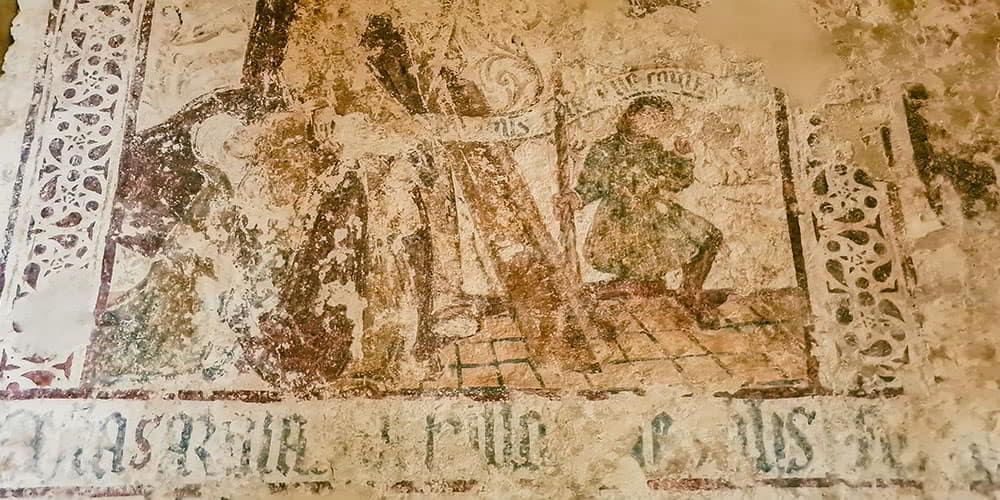 Fragmentary mural paintings inside San Miguel de Lillo, Asturias, showing ancient figures and texts.