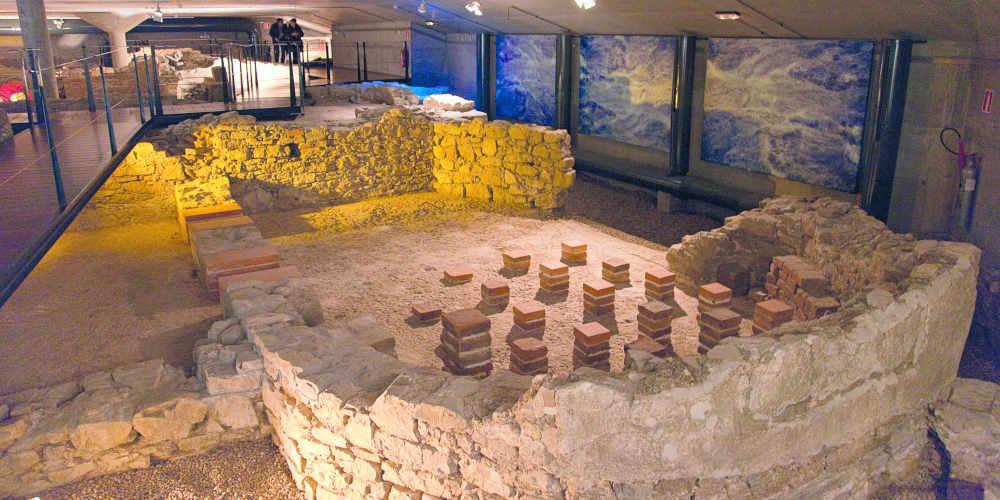 Innenraum des Museums der Römischen Bäder von Campo Valdés in Gijón, mit archäologischen Überresten eines Hypokaustums und erhaltenen Steinmauern.