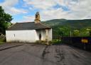 Chapel of San Juan de Silvón, a small white chapel with a belfry, against a mountain backdrop.