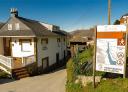 Information sign on the path to the Cascada de Méxica waterfall, next to a traditional house in Villayón.