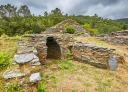 Stone entrance to the hillfort of Pendia amidst vegetation and hills