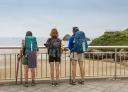 Pilgrims observing the sea from the promenade above Las Cámaras beach