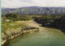 Aerial view of Poo beach with mountains in the background.