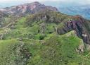 Aerial view of the Joyu El Tejo surrounded by green hillsides and stone walls.