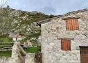 Traditional stone cottage next to meadows in mountainous environment