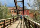Hiker crossing wooden bridge overlooking the mountain village