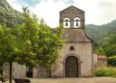 Façade of the pre-Romanesque church of Santo Adriano de Tuñón surrounded by nature.