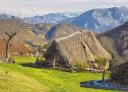 Braña Tuiza con cabaña de techo vegetal y montañas nevadas al fondo