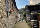 Senderista caminando por aldea con casas de piedra en Veiga da Sarza