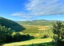 Panoramic view of green meadow and mountains next to the Eo estuary.