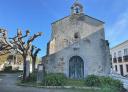 Façade of rural stone chapel with bell tower and pruned trees.