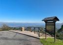 Mirador con valla de madera y cartel innformativo a la derecha con vistas a las montañas