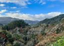 View of the landscape from a hilltop with forests and rock formations.