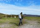 Hikers with two walking sticks crossing a flat trail
