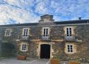 Large stone manor house with balconies, windows under a blue sky with clouds