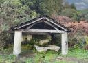 Old stone washhouse with wooden roof in a natural wooded setting